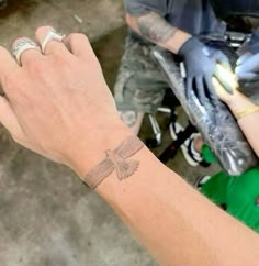 a person with a tattoo on their wrist holding something in one hand and an object in the other