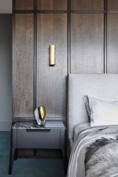 a modern bedroom with wood paneled walls and gray bedding, along with two nightstands