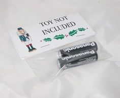 two batteries in plastic bags on top of a white sheet with a toy not included sticker