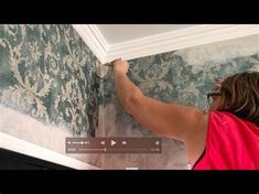 a woman is painting the ceiling in her home