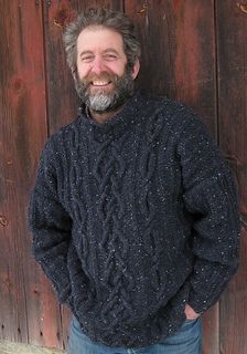 a man standing in front of a wooden wall with his hands in his pockets and smiling