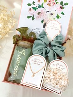 an open box with some items in it on a white tablecloth next to flowers