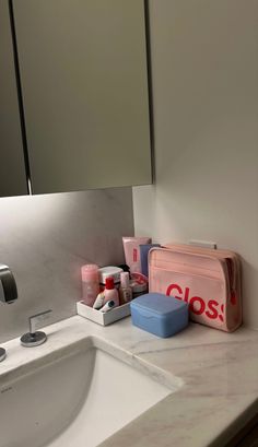 a bathroom sink with toiletries on it and a pink case next to the sink