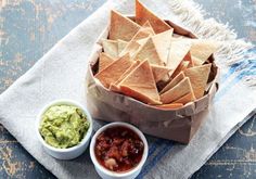 chips, salsa and guacamole in small bowls on a napkin with a towel