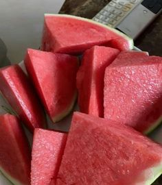 slices of watermelon are on a plate with a remote control in the background