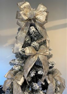 a christmas tree decorated with silver and gold ribbons