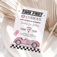 a pink race car birthday party card sitting on top of a plate next to a fan