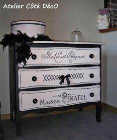 a black and white chest of drawers with name decals painted on it, sitting in a room