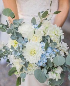 a bride holding a bouquet of white and blue flowers