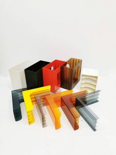 an assortment of different colored vases sitting next to each other on a white surface