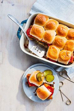 a casserole dish with sliders and pickles in it on a table