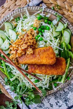 a bowl filled with meat and vegetables next to chopsticks on a woven table cloth