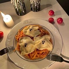 a white plate topped with spaghetti covered in ghost faces