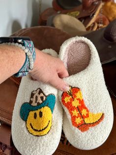 Here’s some fun slippers for the Cowgirls and Cowgirls at heart! These comfy slippers feature a Smiley Face Cowboy and Cowboy Boots. They're incredibly comfy, extra cozy, and feature a rubber bottom ideal for indoor and outdoor wear.Very limited quantity - don't miss out on these fun slippers! Sizing Information:This item is based on women's sizing, and men should size up for the best fit. Size Chart: 6/7: Length 9" 7/8: Length 9 3/4" 8/9: Length 10" 9/10: Length 10 1/2" 11/12: Length 10 3/4" Be Fun Multicolor Non-slip Slippers, Super Soft Closed Toe Casual Slippers, Casual Indoor Slippers With Soft Sole, Super Soft Casual Closed Toe Slippers, Casual Closed Toe Super Soft Slippers, Casual Super Soft Closed Toe Slippers, Cute Indoor Slippers With Round Toe, Cute Multicolor Slippers With Round Toe, Super Soft Comfy Slippers With Round Toe