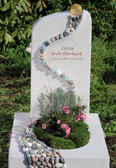 a memorial with flowers and rocks in the shape of a heart on it's base