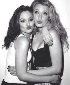 two beautiful young women hugging each other while posing for a photo in black and white