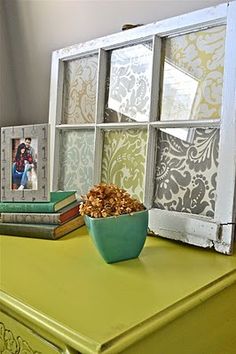 a green table with a bowl of cereal on it and some pictures in the window