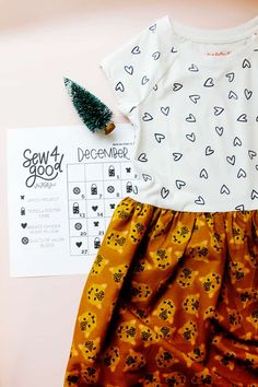 a white shirt and yellow skirt are sitting on top of a pink surface next to a christmas tree