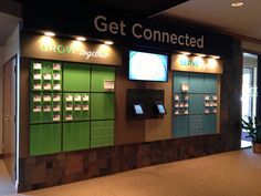 a group of vending machines sitting in front of a wall filled with green boxes