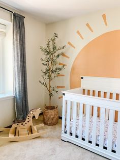 a baby's room with a crib, rocking horse and sun painted on the wall