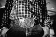 a man in plaid shirt and jeans holding his belt