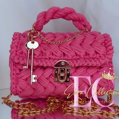 a pink handbag with gold chains and keys on it