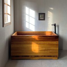 a wooden bathtub sitting in the corner of a room next to a window with sunlight streaming through it