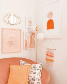 an orange couch with pillows and pictures on the wall