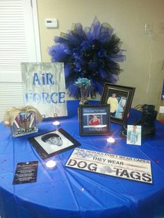 a blue table topped with pictures and framed photos next to an air force sign on top of it