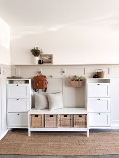 a white bench with some baskets on top of it next to a wall mounted coat rack