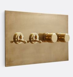 three knobs on the side of a gold wall mounted light switch with white buttons