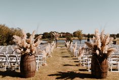 an outdoor ceremony setup with chairs and flowers in buckets on the grass near water