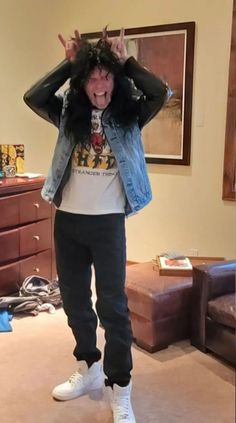 a man standing in a living room with his hands on his head and making the peace sign