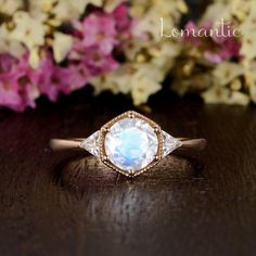 a close up of a ring on a wooden table with flowers in the back ground