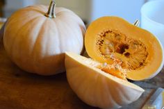 two pumpkins cut in half sitting on a table next to a knife and bowl