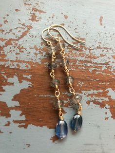 Handcrafted in my Nashville studio, I designed these earrings around the gorgeous orbs of faceted quartz. Each gemstone is filled with black tourmaline flecks and wrapped with solid 14k yellow gold wire. I added perfect ovals of faceted kyanite, also wrapped in 14k gold. These beautiful gemstones hang from 14k yellow gold ear wires. Solid 14k gold construction. 2 3/4 inch long. Ready to ship! Your earrings will arrive gift wrapped. Original design by Dawanna Young. Artisan handmade using recycle 14k Gold Filled Faceted Drop Earrings, Elegant Hand Wrapped 14k Gold Filled Earrings, Elegant Hand Wrapped Drop Earrings, Montana Sapphire Engagement, Montana Sapphire Engagement Ring, Gold Twigs, Diamond Alternative Engagement Ring, Beautiful Gemstones, Montana Sapphire