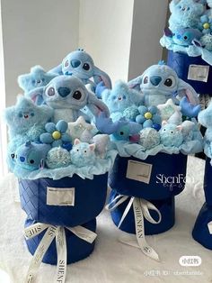 several stuffed animals in blue buckets on a table