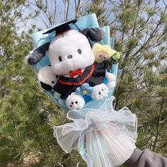 a stuffed animal in a graduation cap and gown is held up by someone's hand