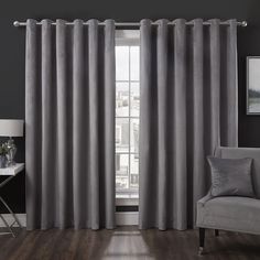 a living room with grey curtains and a white chair in front of the window,