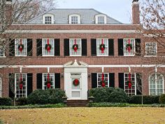 a red brick house with wreaths on the front door