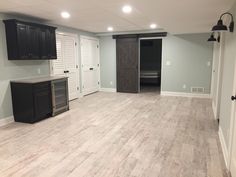 an empty room with black cabinets and white walls, wood floors and gray tile flooring