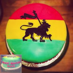 a cake decorated with a lion and flag on top of a wooden table next to a cupcake