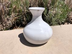 a white vase sitting on top of a cement slab