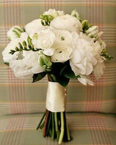 a bouquet of white flowers sitting on top of a couch next to a plaid wall