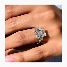 a woman's hand with an engagement ring on her finger and the center stone is surrounded by diamonds