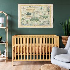 a baby's room with a crib, rocking chair and potted plant