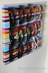 several pairs of sunglasses are hanging on a wall mounted eyeglass holder with multi - colored stripes