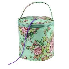 a green floral covered box with purple ribbon on the handle and handles, it is holding a