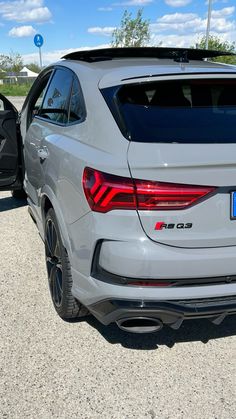 the rear end of a white car parked in a parking lot