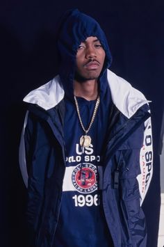 a young man wearing a blue jacket and hoodie standing in front of a black background